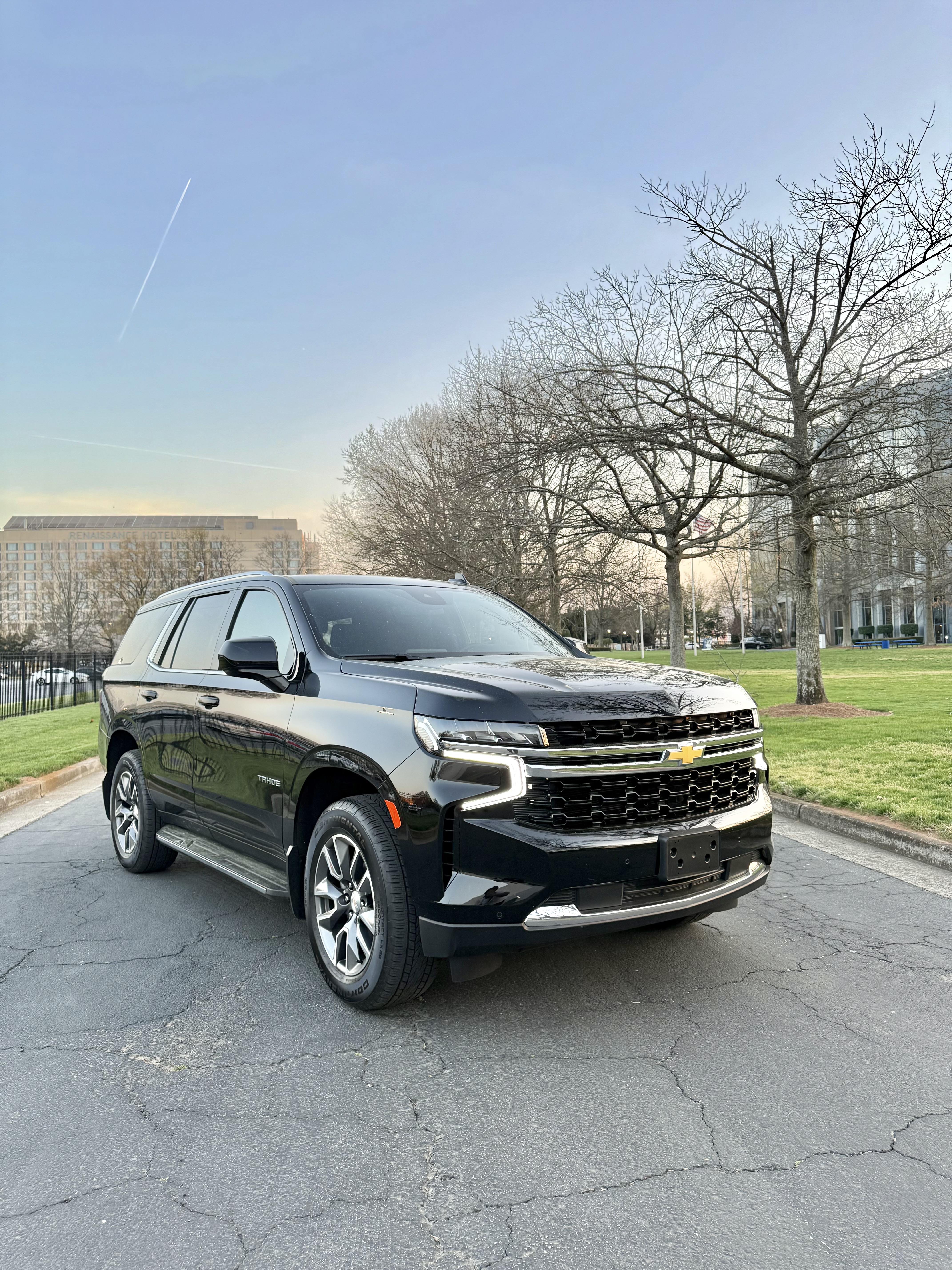 Side view of a white hatchback car parked in front of a house.